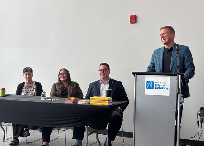 Members of NDIT’s Executive Leadership team share a laugh at the front of a room during an all-employee meeting.