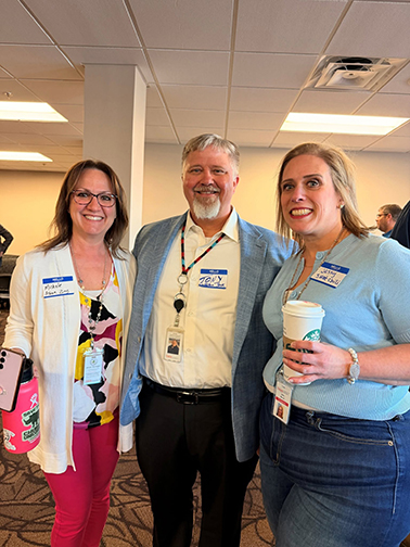 Jessy Wetch and two fellow NDIT team members—a man and woman—happily huddle for a picture at an all-staff event in Bismarck.