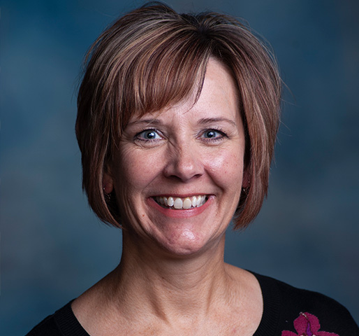 Professional headshot of Kim with a navy background.