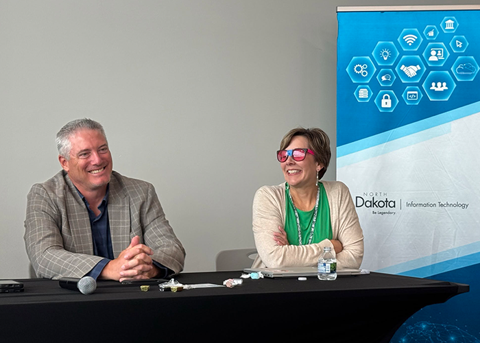 Kim Weis looking happy and wearing silly glasses next to a male executive during an all-team-member meeting in Bismarck, ND.