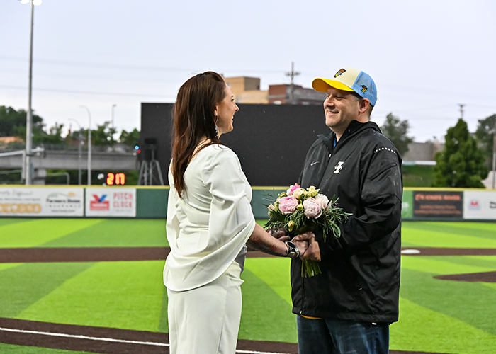 Dana Henry and her husband holding hands while renewing their vows on the field during a Larks baseball game.