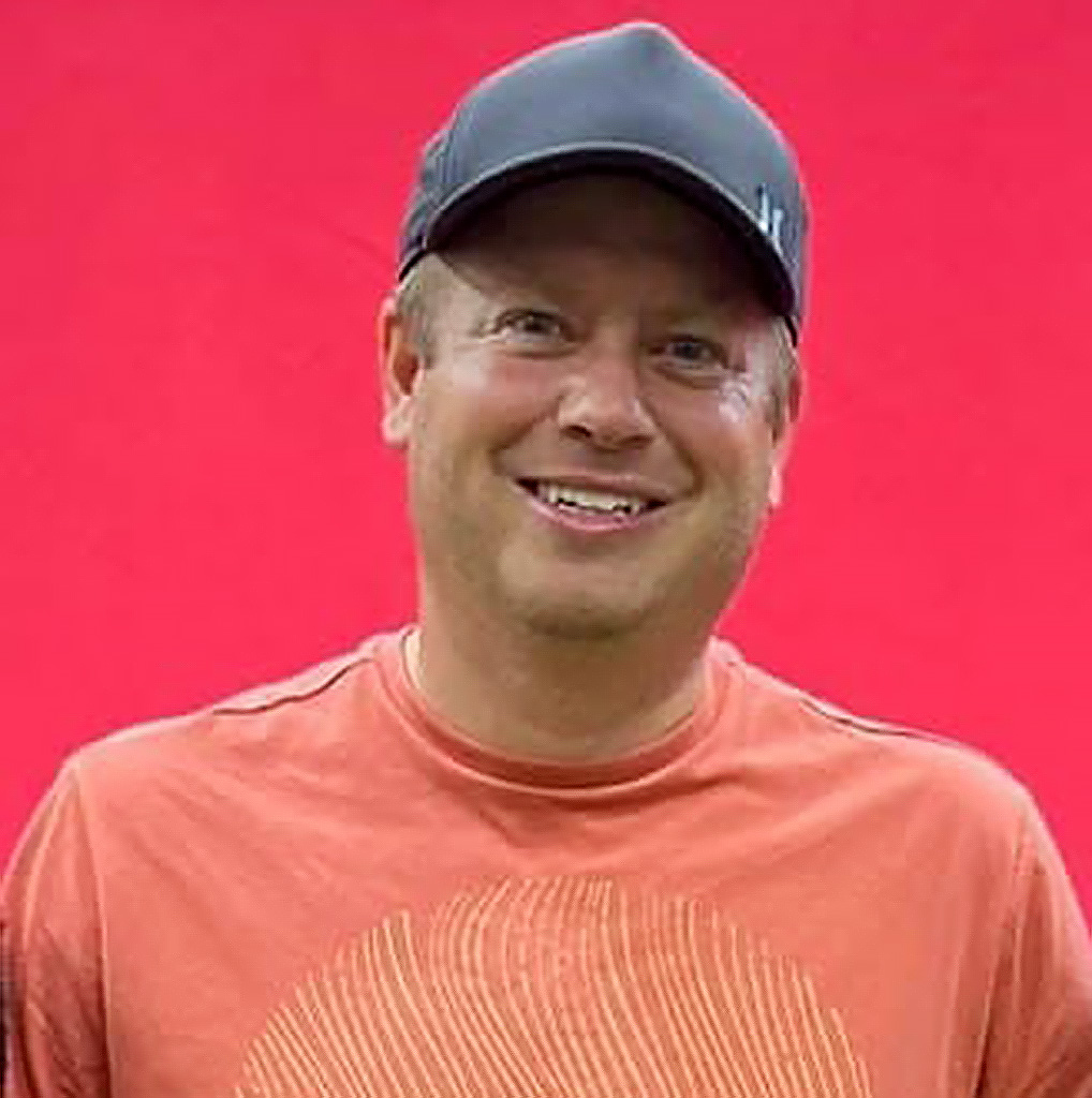 Mike Benz headshot with a red background.