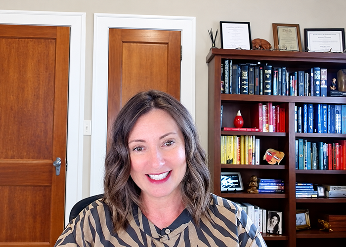 Monique Durgin smiles in her North Fargo office, with a bookshelf and two doors in the background.