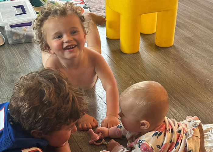 Surrounded by toys, Raulie Berthold’s three kids—two little boys and a baby girl—play happily together on a hardwood floor.