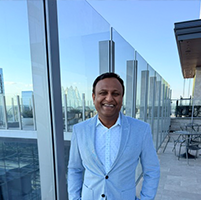 Professional headshot of Uday Madireddy wearing a light colored shirt and grey suit jacket.