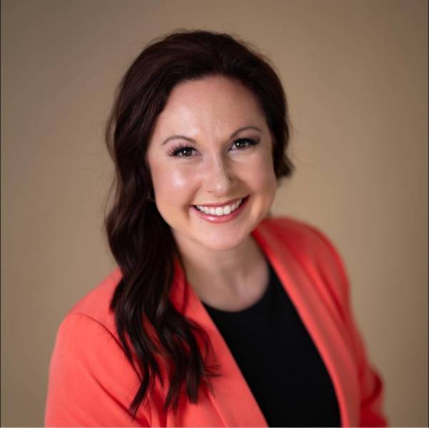 A professional headshot of Dana Henry a caucasian woman with long black hair, wearing a black shirt and red blazer.