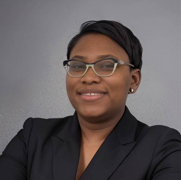 A professional headshot of Ingrid Clarke an African American woman wearing a black suit jacket and glasses.