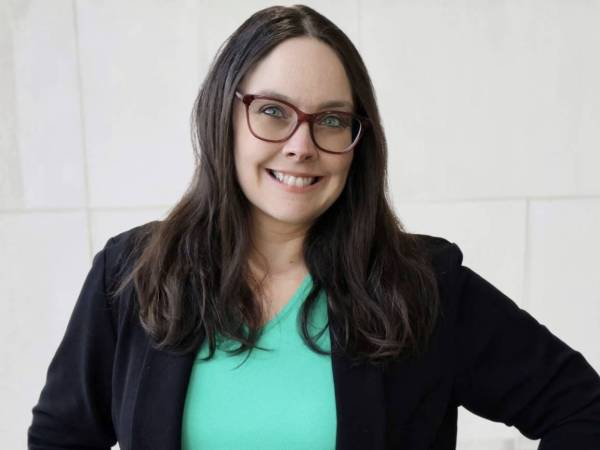 A professional headshot of Colleen T. wearing a mint-colored top, black blazer, and glasses.