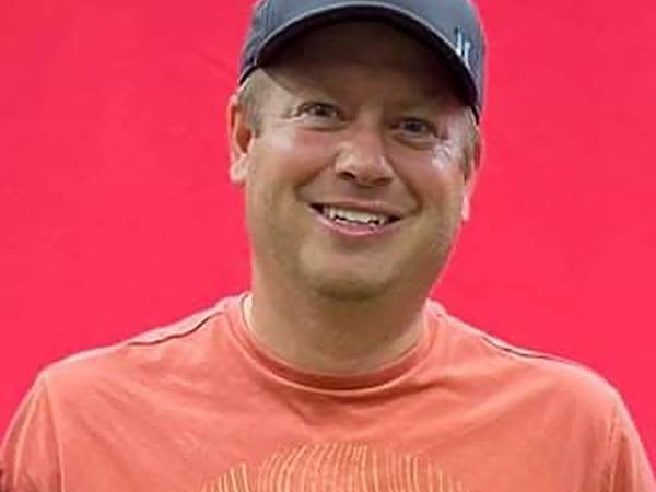 Mike Benz headshot with a red background.