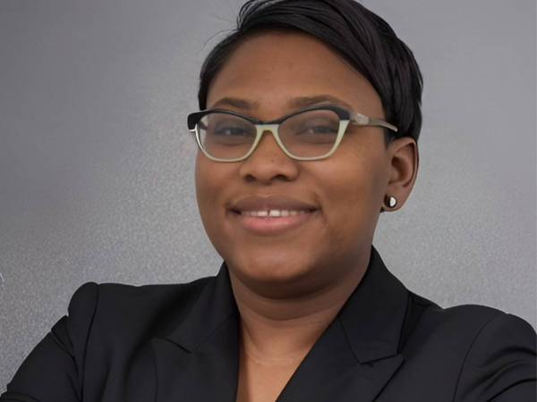 A professional headshot of Ingrid Clark, NDIT Technology Outreach Apprentice, wearing glasses and her black blazer.