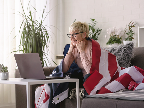Middle-aged woman sitting on a couch looking at a laptop.