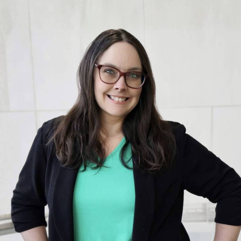 A professional headshot of Colleen T. wearing a mint-colored top, black blazer, and glasses.