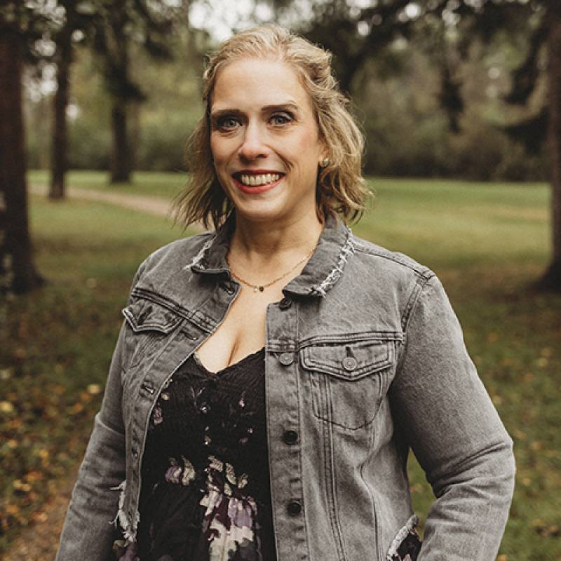 Jessy Wetsch's professional headshot with her wearing a black flowered blouse and grey, jean jacket.