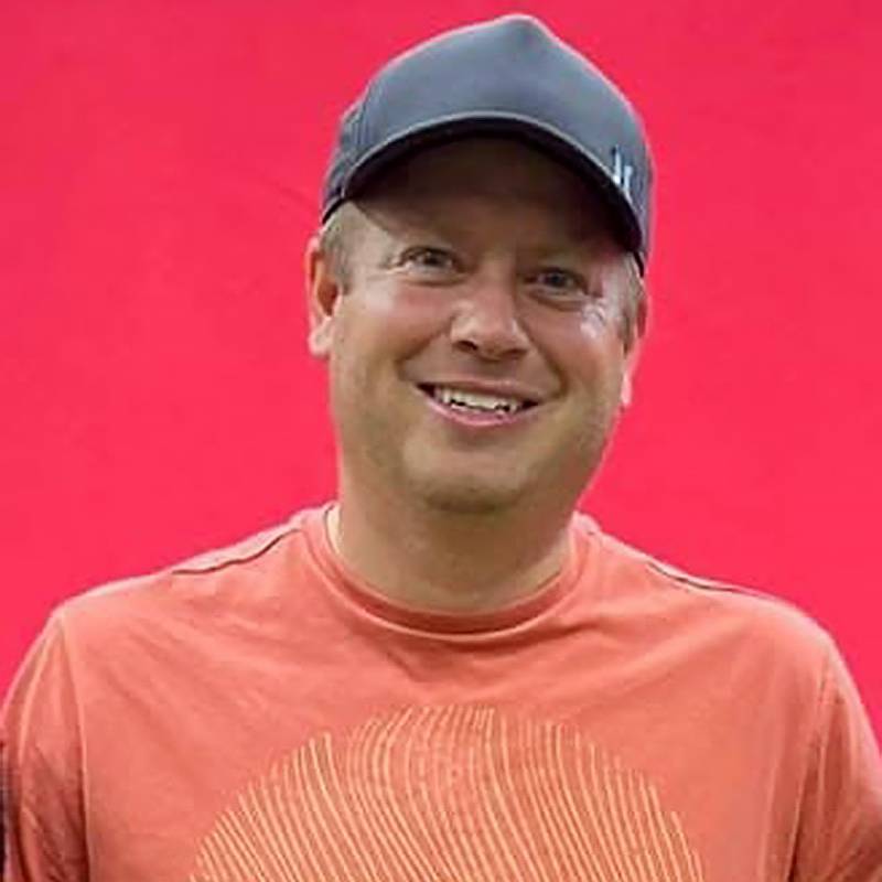 Mike Benz headshot with a red background.