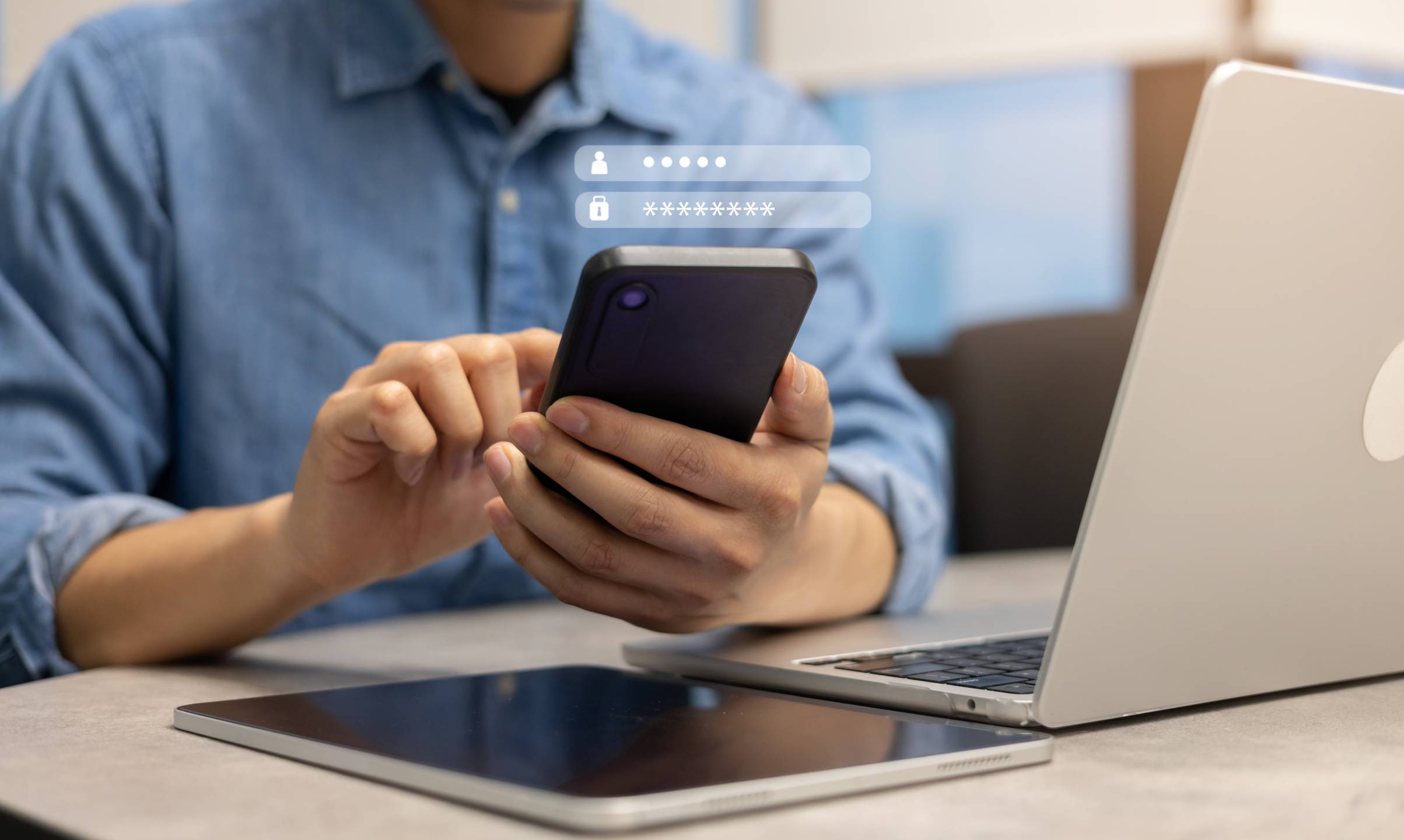 Man holds a smartphone next to a laptop and tablet, with password icons shown to represent data privacy and account security.