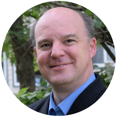 Robert Hart, Senior Business Analyst, has gray hair, and is dressed in a light blue collared shirt and a dark blue suit jacket.
