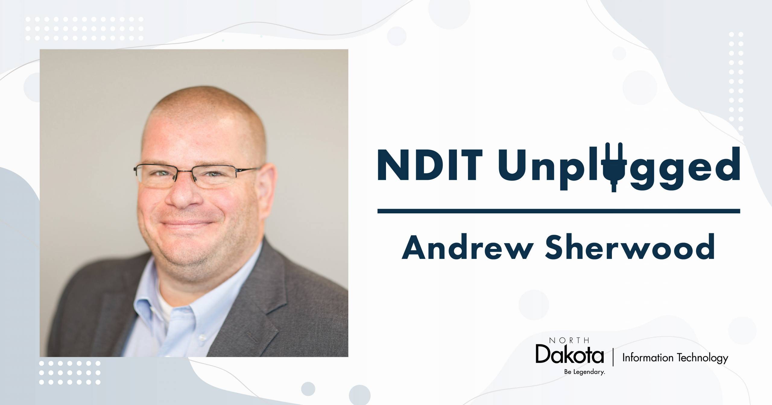 A professional headshot of Andrew Sherwood, NDIT Enterprise Portfolio Manager, wearing a gray suit coat and blue dress shirt with the text NDIT Unplugged Andrew Sherwood