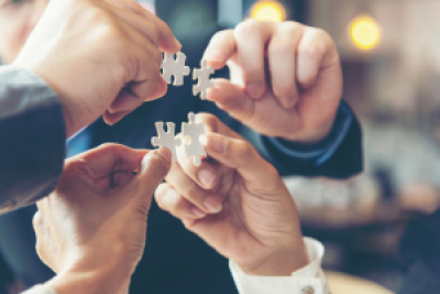 Hands holding puzzle pieces showing team work. 