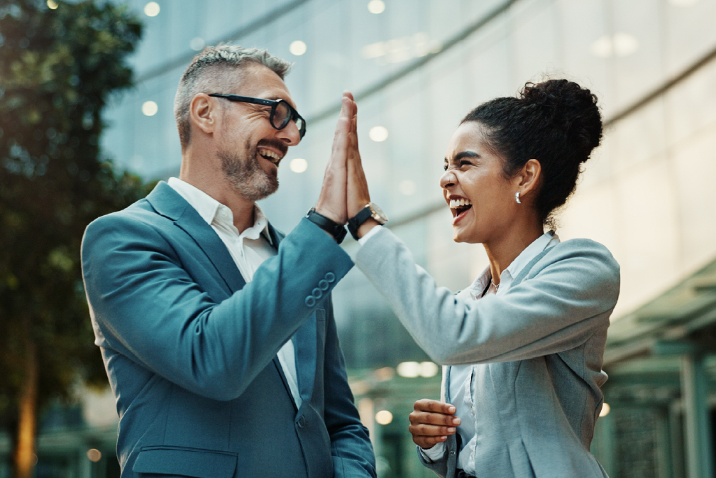 Two coworkers—a man and a woman—give a high-five after securing Siteimprove for their North Dakota government website.